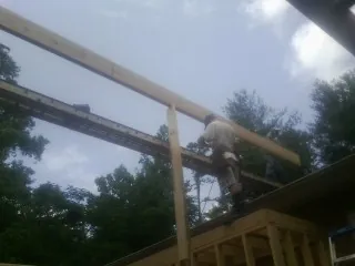 Carpenter setting a ridge beam over a new addition frame — Ice Dam Removal by Roofing Brothers in Point Of Rocks