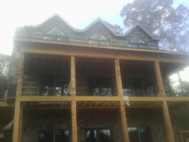 Dormers and porch framing on a large log home under construction — Roof Coating work by our crew in Point Of Rocks