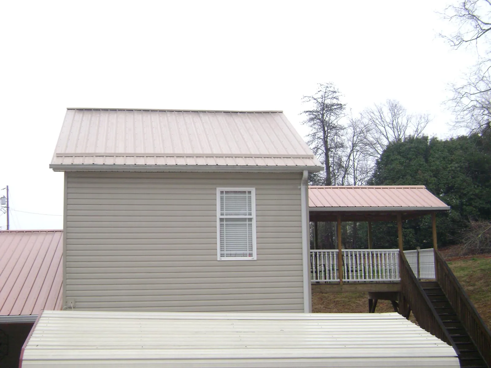 Tan metal roofs on a two story addition and attached porch, from a Roof Replacement job in Point Of Rocks