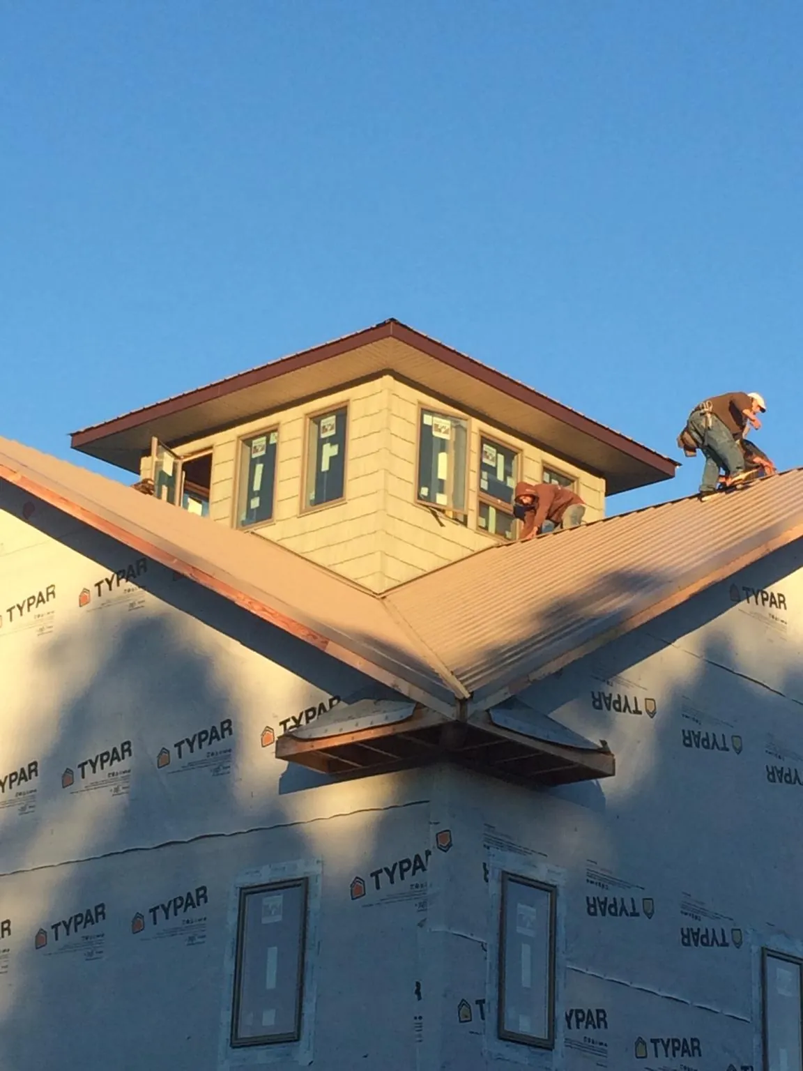Roofers working around a rooftop cupola on a new metal roof at sunset — Roof Waterproofing in Point Of Rocks by Roofing Brothers